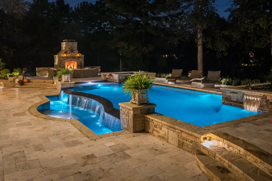 Aerial view of a backyard pool with a travertine deck